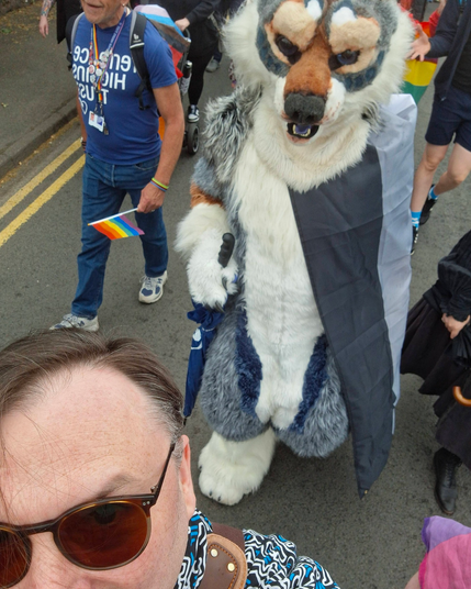 Me in fursuit wearing an ace flag during the Arran pride march