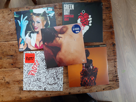 A photo of some vinyl records, from top left, going clockwise: Blink-182 - Enema of the State, Green Day - American Idiot, Little Sims - Sometimes I Might Be Introvert, Paramore - Riot!, and Harry Styles - Harry Styles.