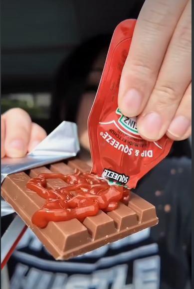 Someone putting tomato ketchup on a kitkat