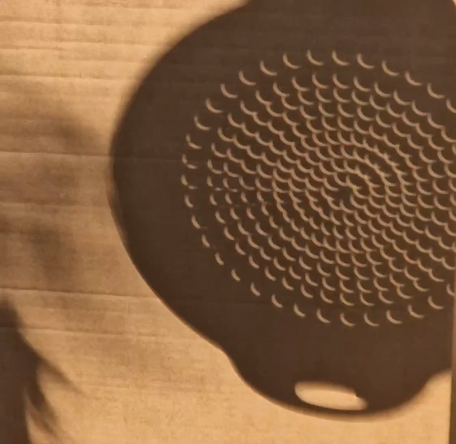The shadow of a colander during a partial eclipse, so instead of the drainage holes being circles they're crescents