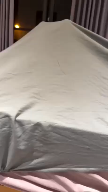 A cat under a blanket keeping it up with its 2 back legs
