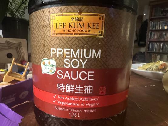 Large bottle of soy sauce with a band on it that says “no added additives” and “vegetarians and vegans” with a tick next to each.