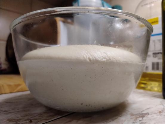 Close up of a glass bowl full of puffy risen dough 