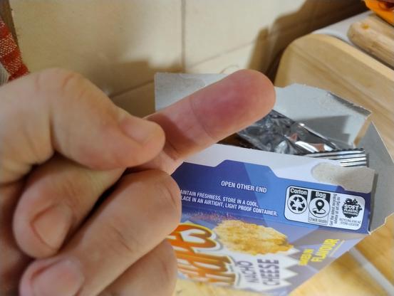 Me presenting a raised middle finger to a box of nacho cheese Shapes that had been opened at the end that clearly says