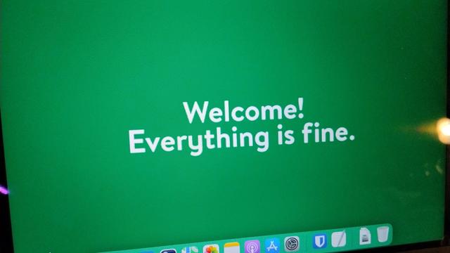 A macOS desktop with the wallpaper set to a solid green with the text