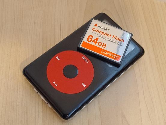 A red and black U2 Special Edition iPod with a 64GB compact flash card sitting on top of it.