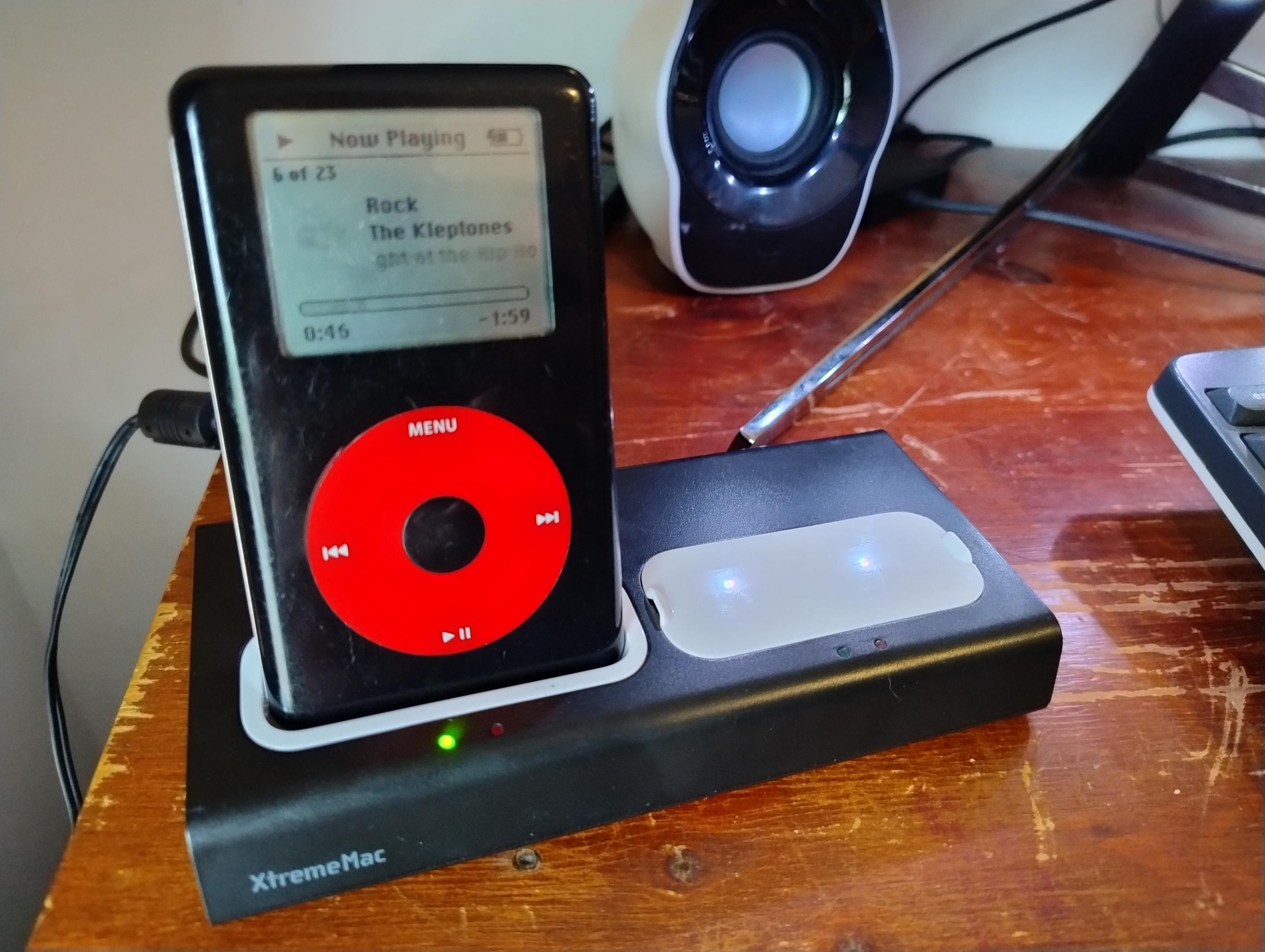 Black and red U2 Special Edition iPod in an XtremeMac dual charging dock on a wooden desk