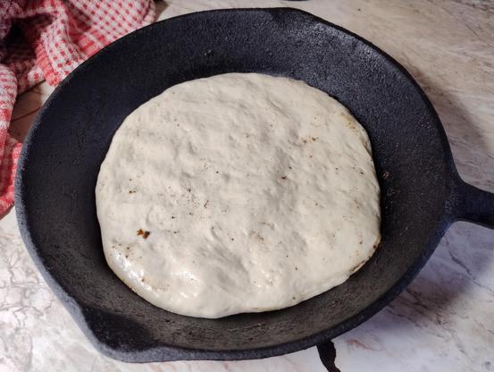 Uncooked pizza dough in the bottom of a cast iron skillet 