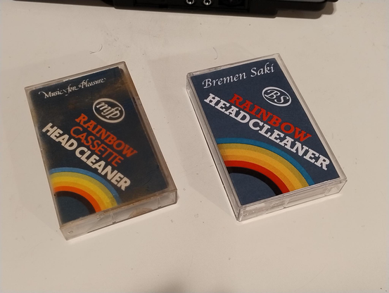 Two audio tape cases, one for a classic Rainbow branded cassette head cleaner and one that is styled very similarly that's an album by Bremen Saki called Rainbow Headcleaner.
