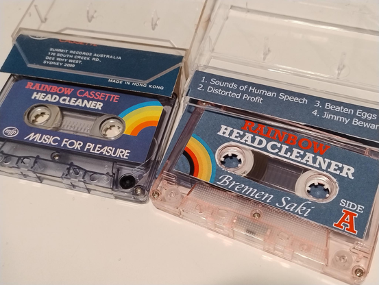 Two audio cassettes in open cases, one is a Rainbow branded cassette head cleaner and one that is styled very similarly that's an album by Bremen Saki called Rainbow Headcleaner, side A.