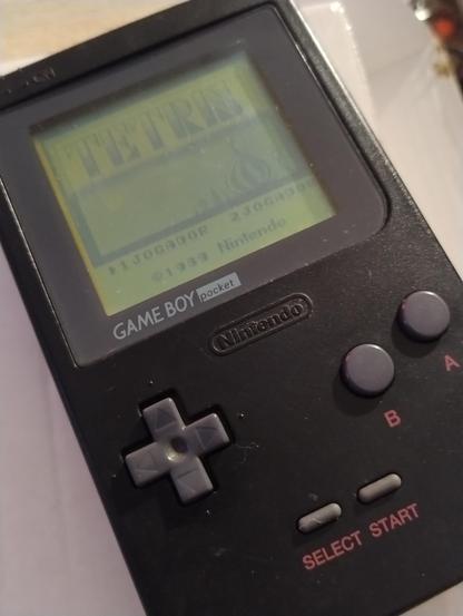 A black Game Boy Pocket displaying the Tetris start screen