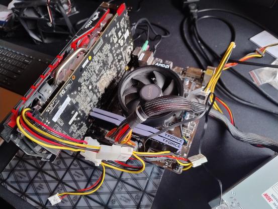 A small PC motherboard with a video card and power supply attached outside of a case