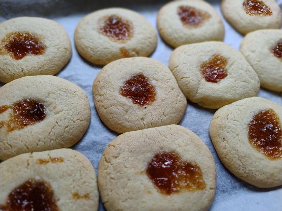 Biscuits with drops of jam in the centre lined up on a tray