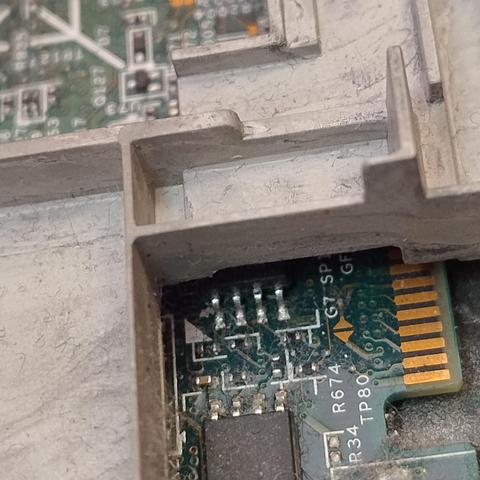 A small chip on a board poking out cheekily from under a big section of metal support framework 