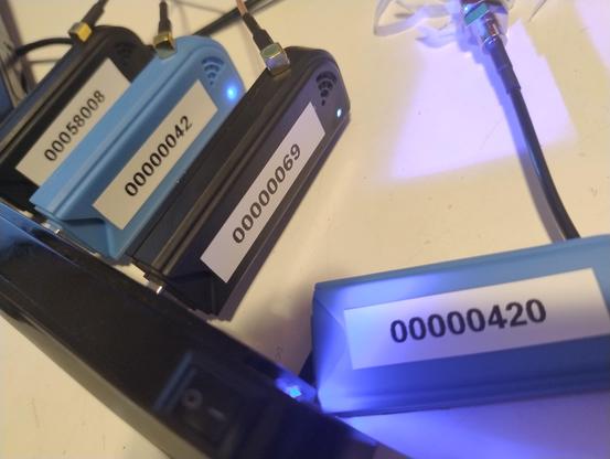 Four USB radios on a table with number labels reading 00000420, 00000069, 00000042, and 00058008