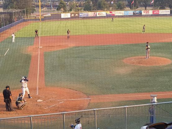 A baseball game in progress, a person in a white uniform is at bat