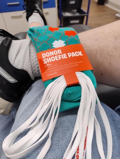 POV photo of my legs raised up with a blood donor promotional socks pack on display