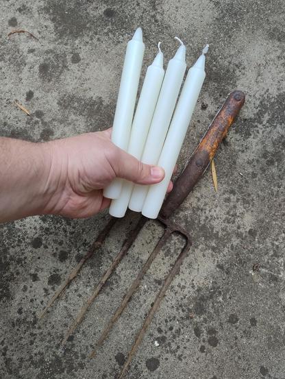 A garden fork without a handle, and me holding up four candles in front of it.