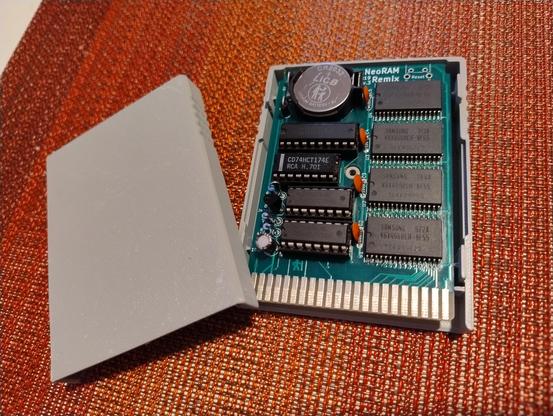 A cartridge board with ram chips on it with a grey plastic case for it to exist in