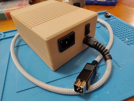 A beige box with a socket for a mains power cable, a switch, and a cable ending in a square plug