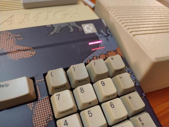 Close up of an illuminated Amiga 500 power led next to a power supply brick