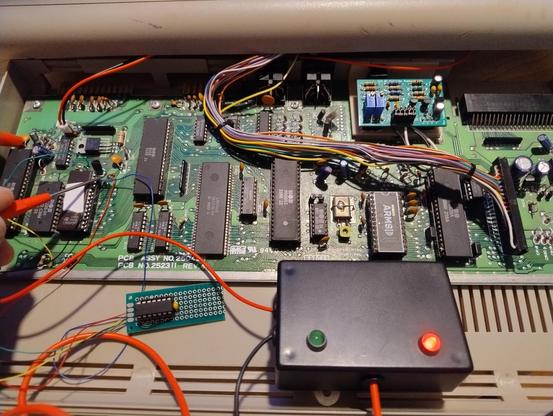 Inside of a Commodore 64 with a small chip on a piece of perfboard at the bottom of the case with wires from it soldered to various points