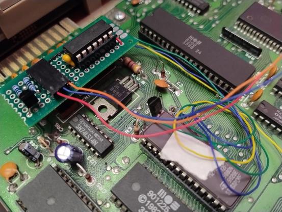Close up of a Commodore 64 board with a dodgy bit of perfboard over the power led connection with wires running off to various other components