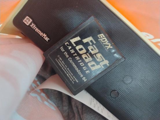 A vintage epyx fast load cartridge for the Commodore 64 on top of an Xtreme Mac branded speaker dock