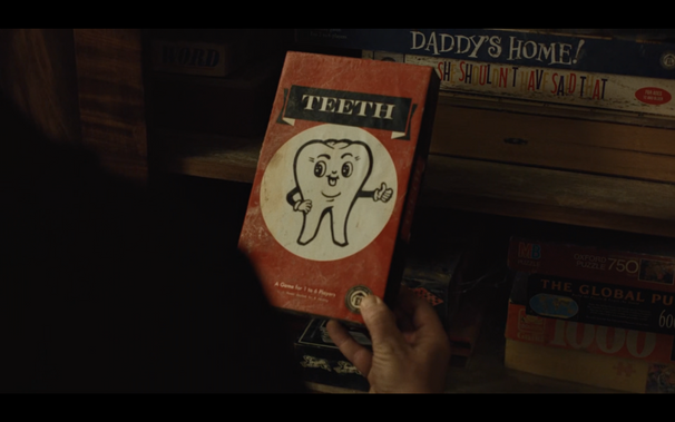 Someone holding up a vintage board game style box labelled TEETH with a picture of a happy looking anthropomorphic cartoon tooth under it