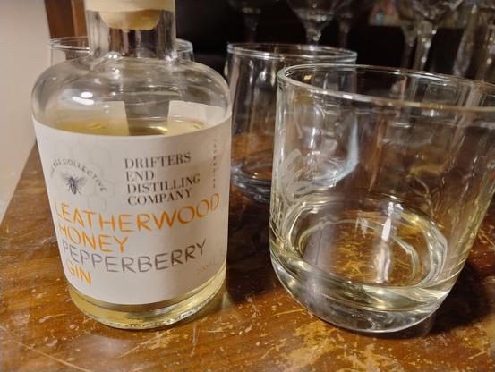 A bottle of Leatherwood Honey Pepperberry Gin next to a glass of same