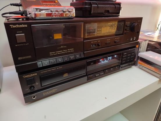 A Technics tape deck from the late 1980s on top of a CD player from a similar era.