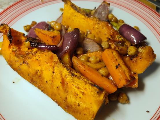Big slices of roasted pumpkin on a plate with carrots, chickpeas, celery, capsicum and onion 