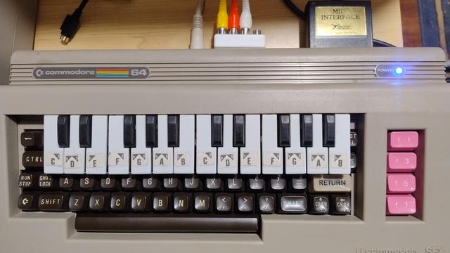 A Commodore 64 with a piano key overlay on top of it. It also has pink function keys and a MIDI cartridge cheekily poking out the back