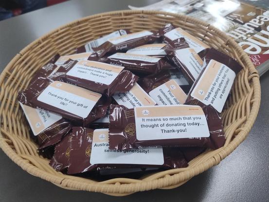 Individual wrapped Tim Tams in a basket with stickers on them thanking blood donors today