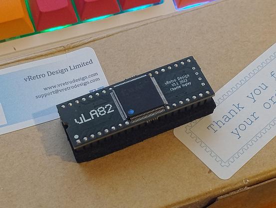 A chip on a small PCB labelled ULA82 on top of a box sent by vRetro Design 