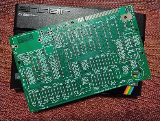 An unpopulated motherboard PCB for a ZX Spectrum on top of a ZX Spectrum.