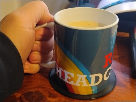 Coffee in a mug printed with a rainbow logo and the word 