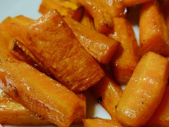 Sliced carrot pieces lightly roasted, glistening, slightly browned at the edges
