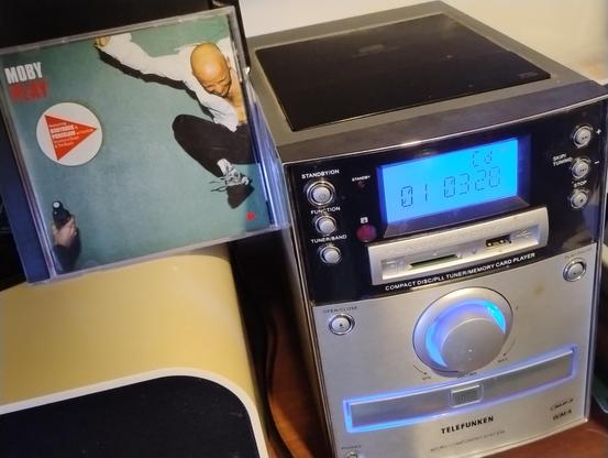 A copy of Moby's album Play next to a small silver and black Telefunken mini system.