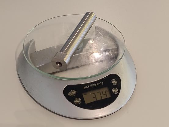 A metal rod on a kitchen scale that weighs 374 grams 