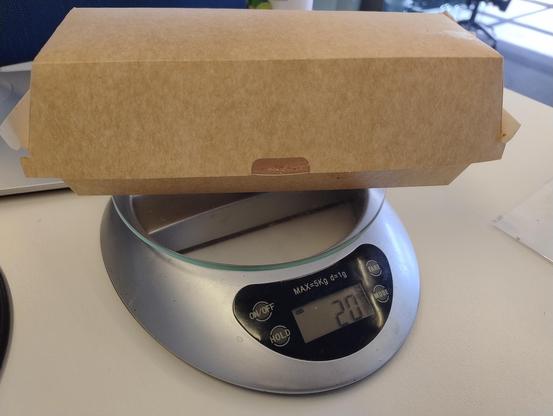 A cardboard box balanced on kitchen scales, the display showing 20 grams 