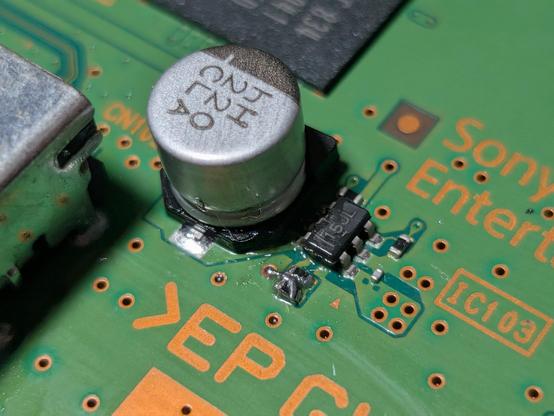 Close up picture of a circuit board with a tiny wire bridged across two tiny resistors 
