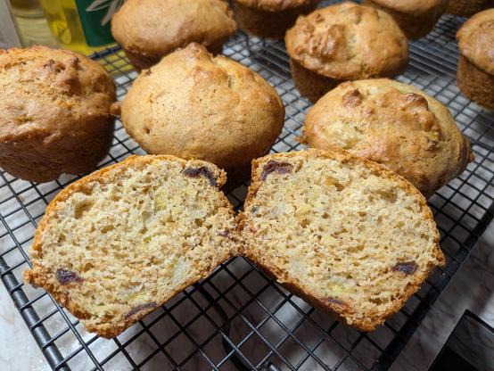 A muffin cut in half on a cooling rack with other uncut muffins 