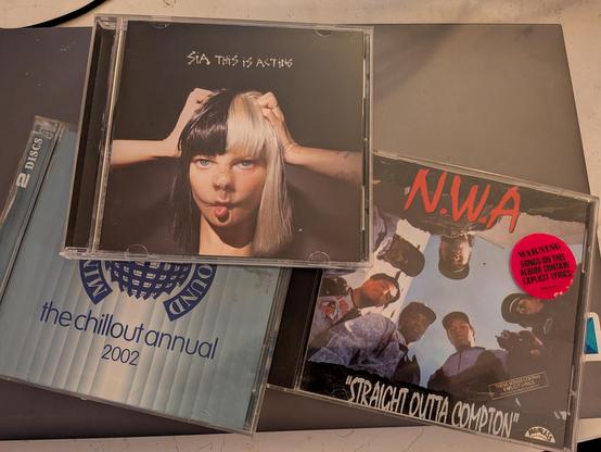 Three CDs laid out together, The Ministry of Sound 2002 Chillout Annual, NWA's Straight Outta Compton, and Sia's This is Acting