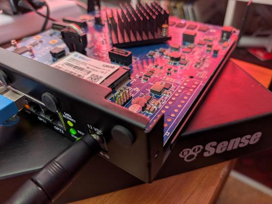 An appliance case, open, with a pfSense logo on it and the motherboard visible with a 128 gig msata SSD installed